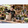 Продавцы локального рынка собирают общий заказ из продуктов, хлеба и цветов