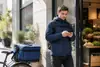 Курьер проверяет маршрут на смартфоне рядом с велосипедом и термосумкой